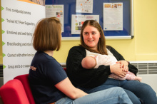 Peer supporter talking to Mum while feeding her baby